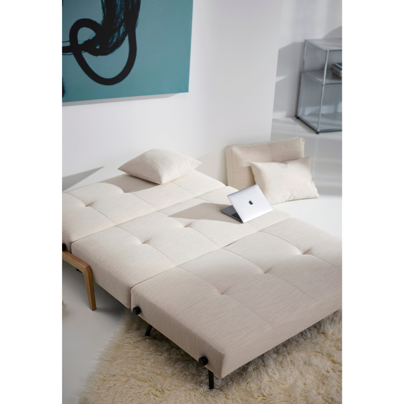 The Cubed Queen Size Sleeper Sofa with Wood Legs from Innovation Living with lacquered oak legs and blida sand grey 612 upholstery in a bedroom space. all-groups