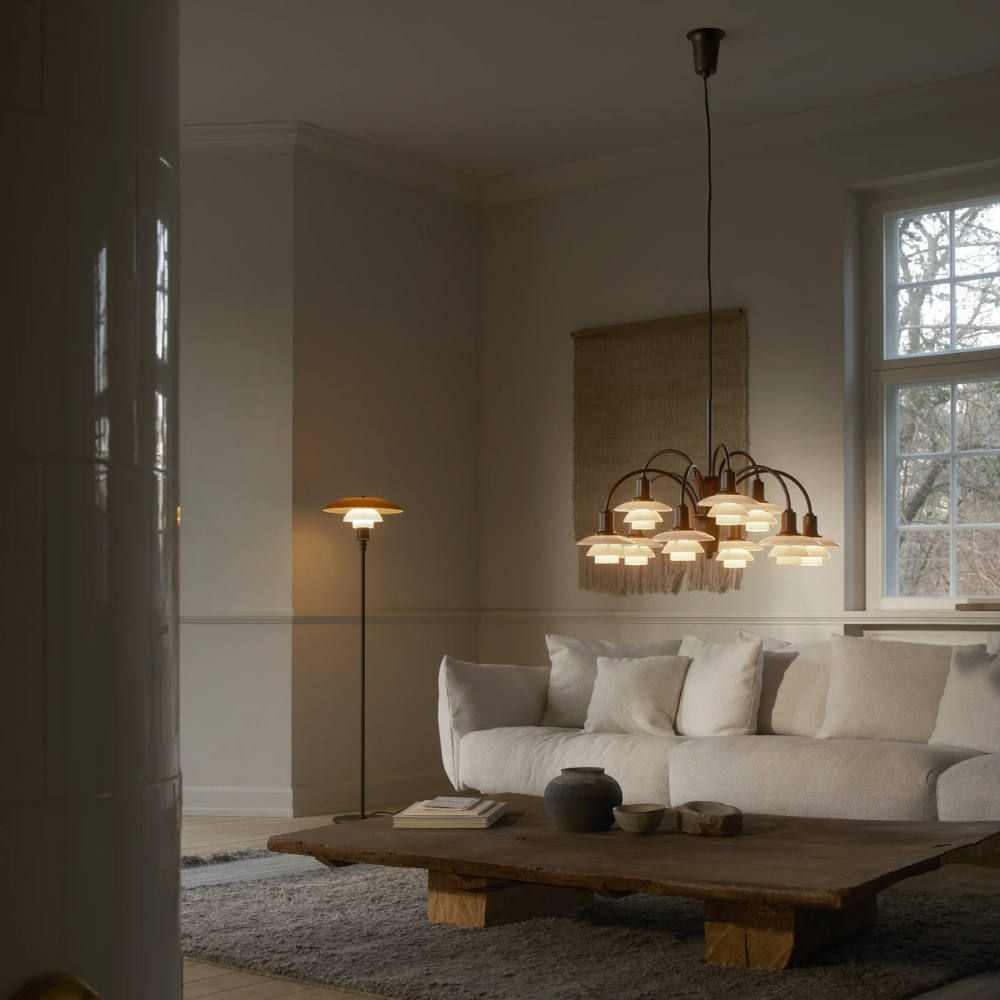 The PH 1/1 Chandelier, 9-Light by Louis Poulsen in a living room turned on.