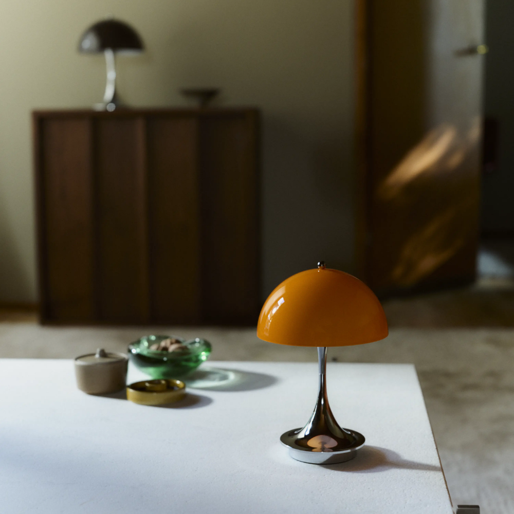 The Panthella 160 Portable Lamp from Louis Poulsen in Original Opal Orange on a dining table turned off.
