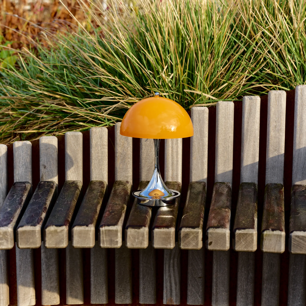 The Panthella 160 Portable Lamp from Louis Poulsen in Original Opal Orange outdoors.