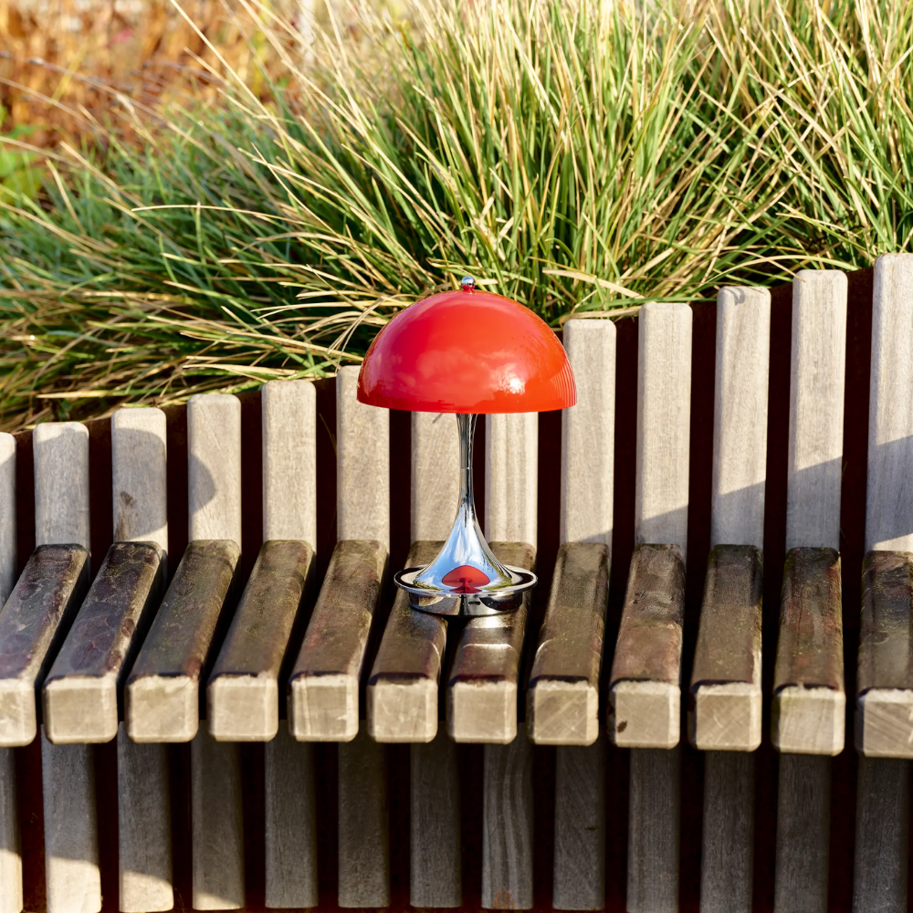 The Panthella 160 Portable Lamp from Louis Poulsen in Original Opal Red outdoors.