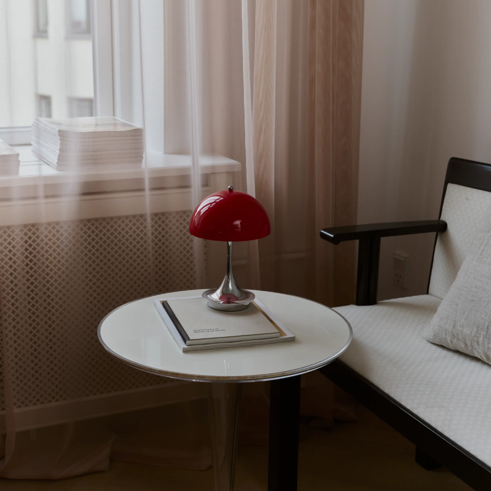 The Panthella 160 Portable Lamp from Louis Poulsen in Original Opal Red on a side table turned off.