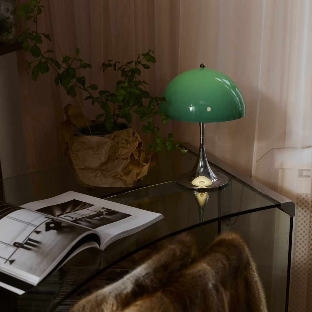 The Panthella 250 Portable Table Lamp from Louis Poulsen in Original Opal Green on a side table.