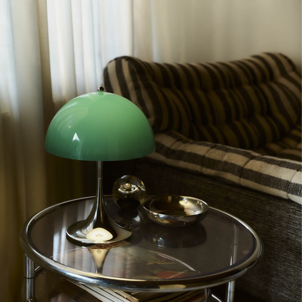 The Panthella 250 Portable Table Lamp from Louis Poulsen in Original Opal Green on a side table in a living room.