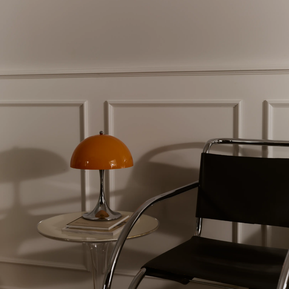 The Panthella 250 Portable Table Lamp from Louis Poulsen in Original Opal Orange turned off on a side table.