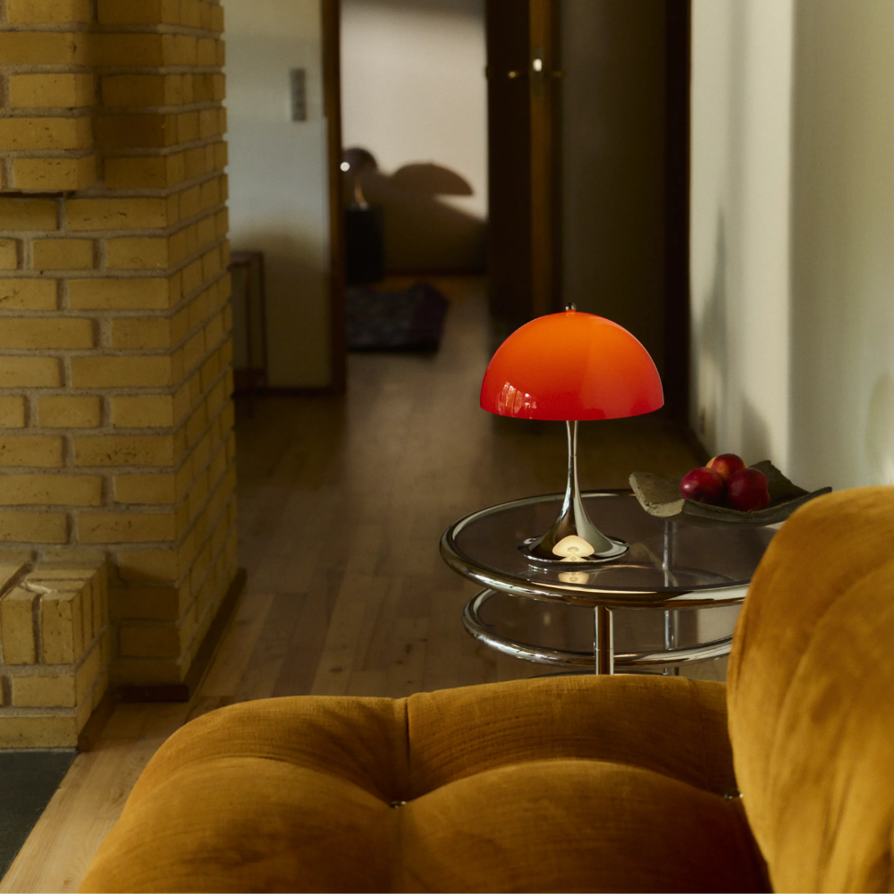 The Panthella 250 Portable Table Lamp from Louis Poulsen in Original Opal Red turned on in a living room.
