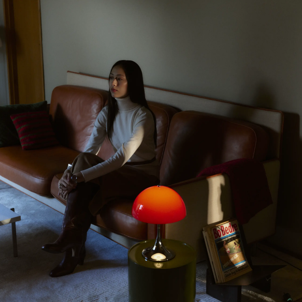 The Panthella 250 Portable Table Lamp from Louis Poulsen in Original Opal Red turned on at night.