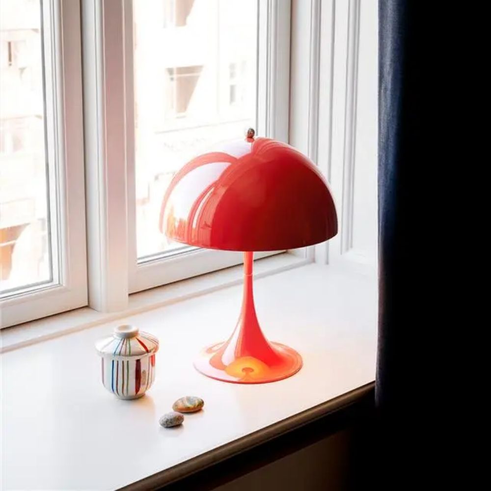 The Panthella 250 Portable Table Lamp from Louis Poulsen in Coral in a windowsill.