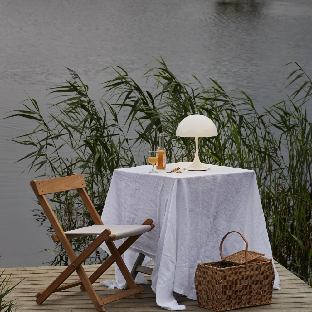 The Panthella 250 Portable Table Lamp from Louis Poulsen in Opal white on an outdoor table.