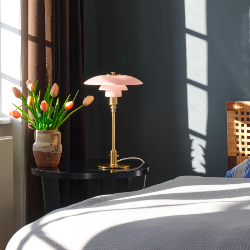 The pale rose PH 3/2 Glass Table Lamp from Louis Poulsen in a primary bedroom.