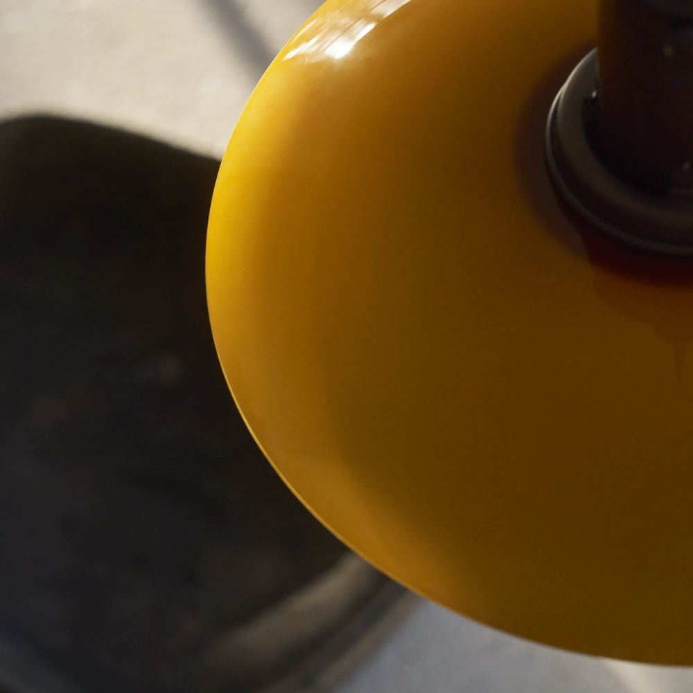 A close up of the lacquered brass suspension and amber glass top shade of the PH 3/3 Pendant Centenary Edition by Louis Poulsen.