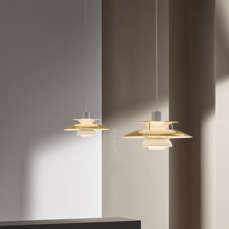 The PH 5 Mini Pendant from Louis Poulsen in brass in a living room.