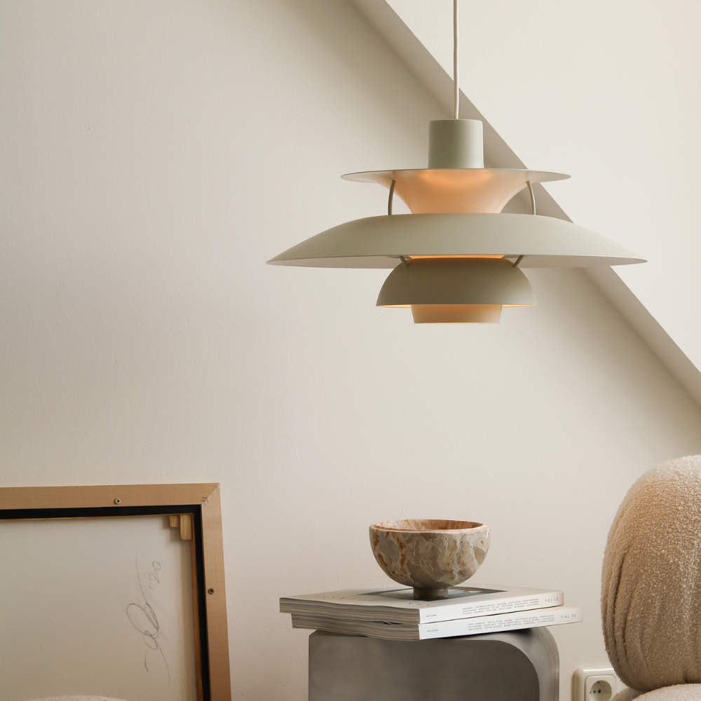 The PH 5 from Louis Poulsen in monochrome pale pewter in a living room turned on.