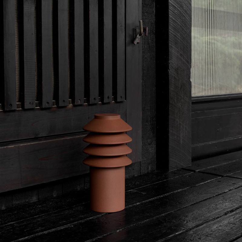 The Short Bysted Garden Bollard from Louis Poulsen in corten beside a doorway.
