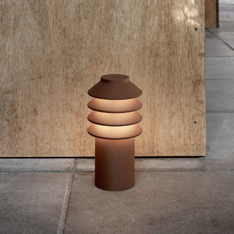 The Short Bysted Garden Bollard from Louis Poulsen in corten in an outdoor living area.