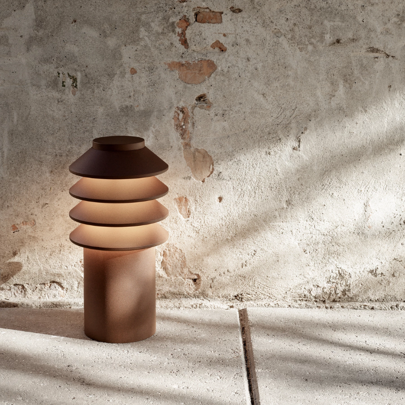 The Short Bysted Garden Bollard from Louis Poulsen in corten in an outdoor living space.