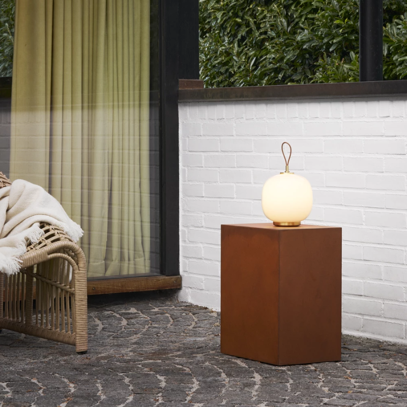The VL 45 Radiohus Portable Lamp from Louis Poulsen in opal white glass in a outdoor living area.