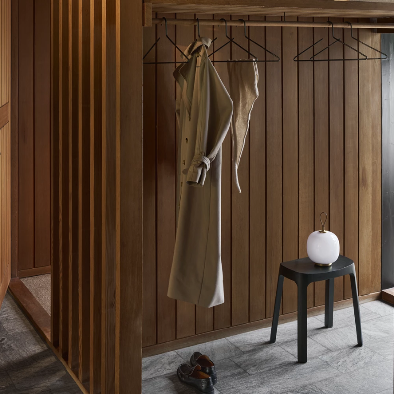 The VL 45 Radiohus Portable Lamp from Louis Poulsen in opal white glass within a walk in closet.