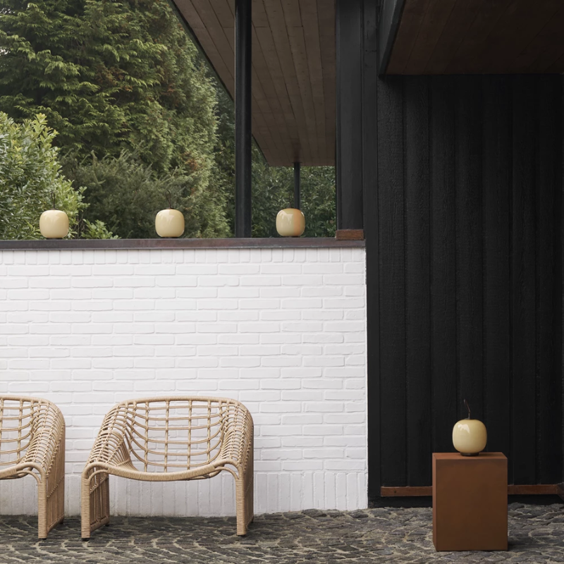 The VL 45 Radiohus Portable Lamp from Louis Poulsen in pale yellow glass in an outdoor space.