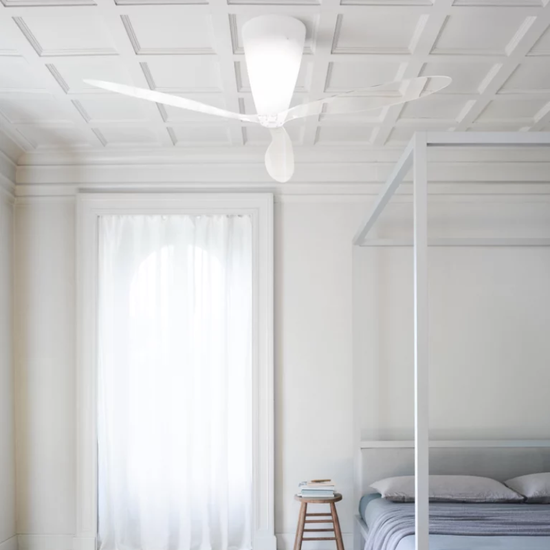 The Blow Ceiling Fan from Luceplan with transparent blades in a primary bedroom.