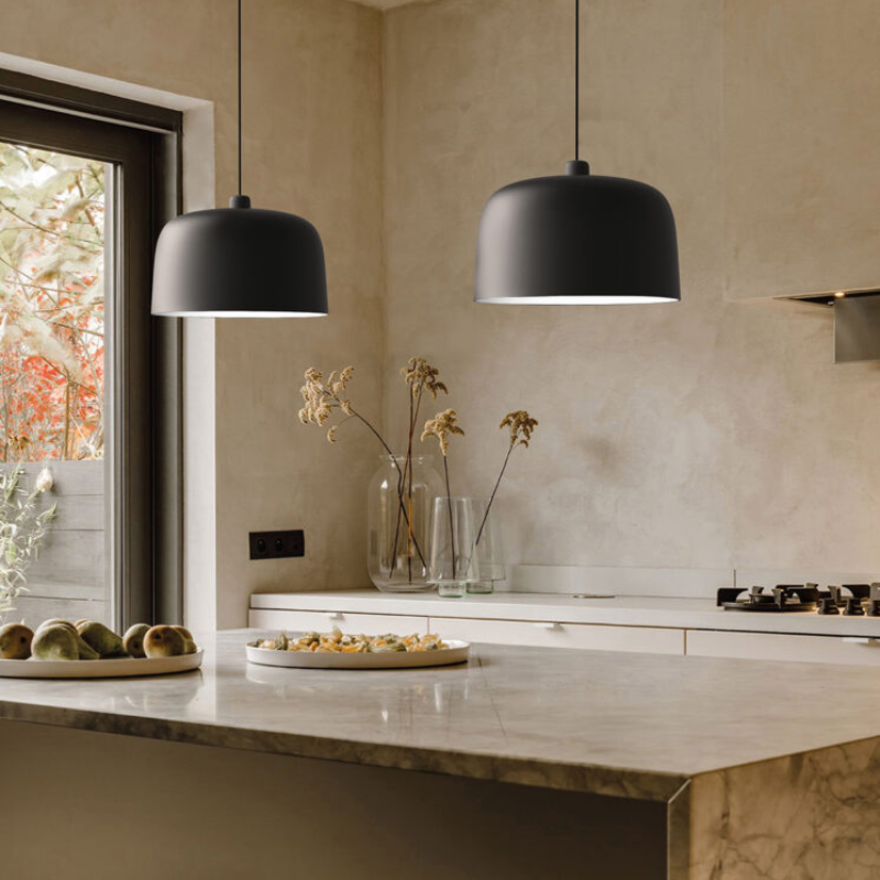The Zile Pendant from Luceplan in matte black in a kitchen above a counter.