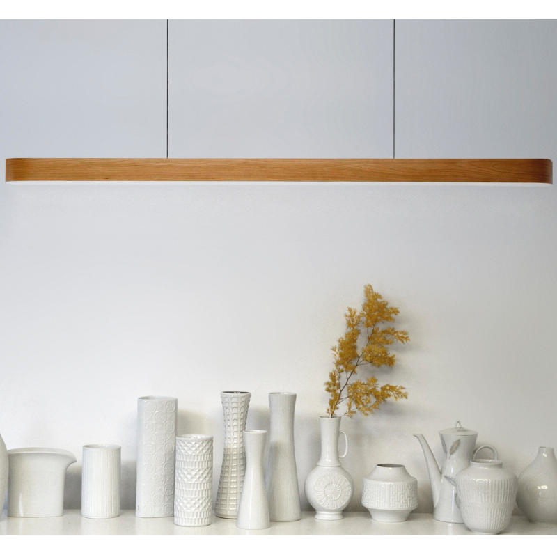 The Long I-Line Suspension from LZF lamps with the natural cherry veneer in a kitchen and dining setting.