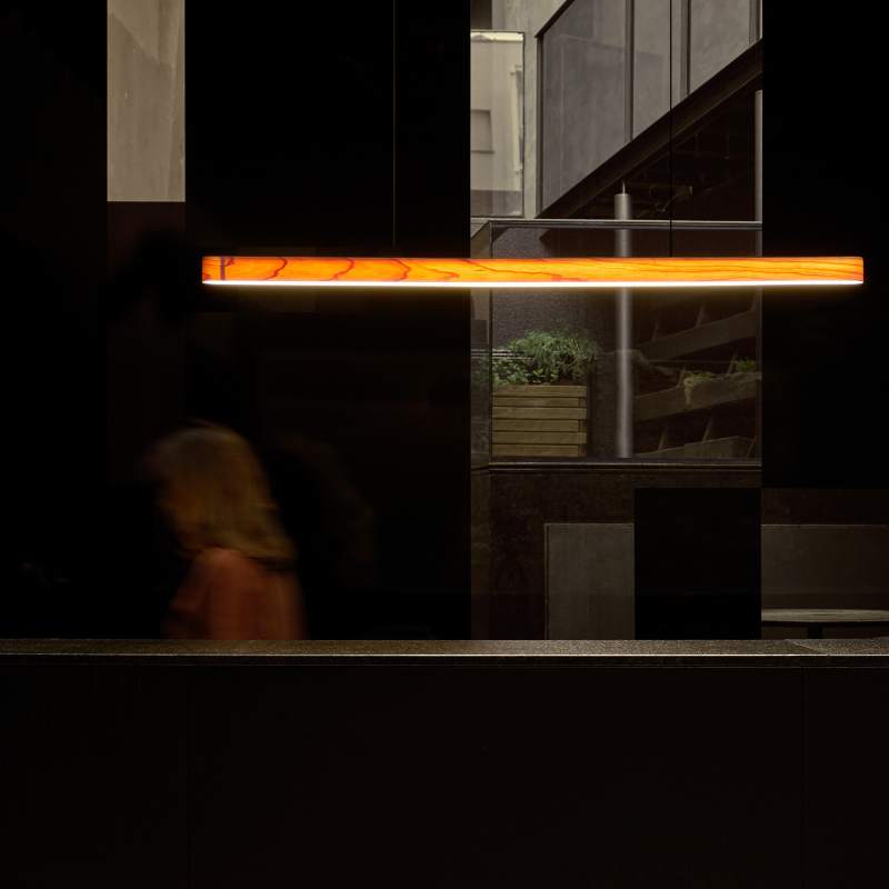 The Long I-Line Suspension from LZF lamps with the natural cherry veneer in a living space.