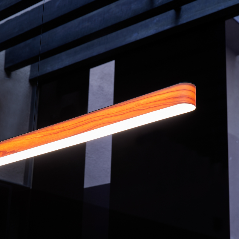 The Long I-Line Suspension from LZF lamps with the natural cherry veneer in a lounge.