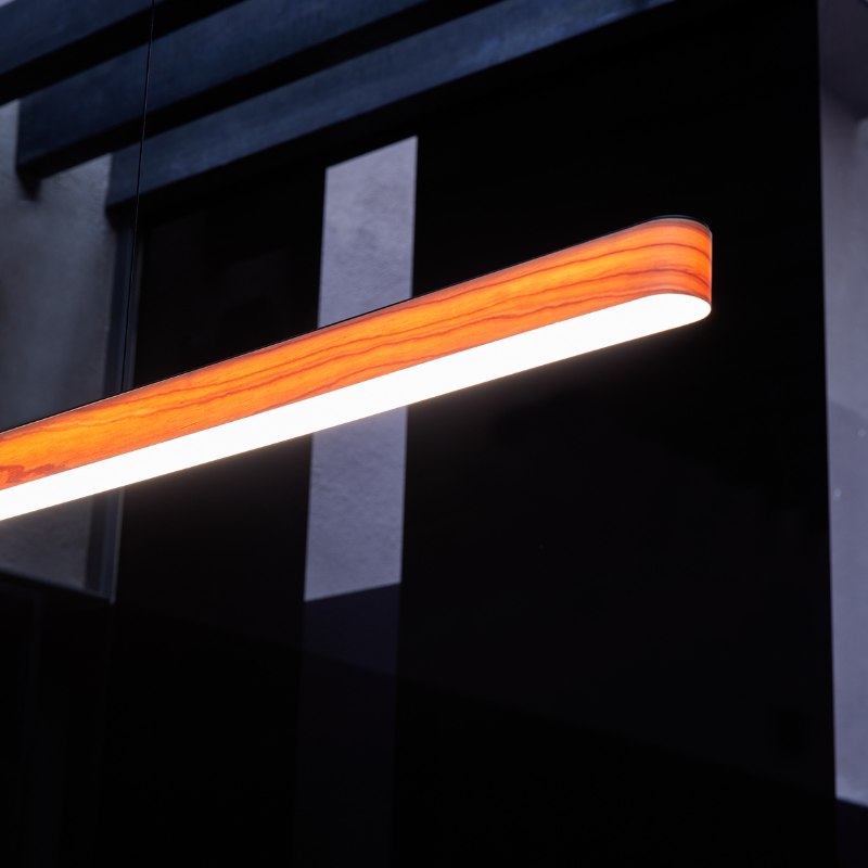 The Short I-Line Suspension from LZF lamps with natural cherry veneer in a commercial space.