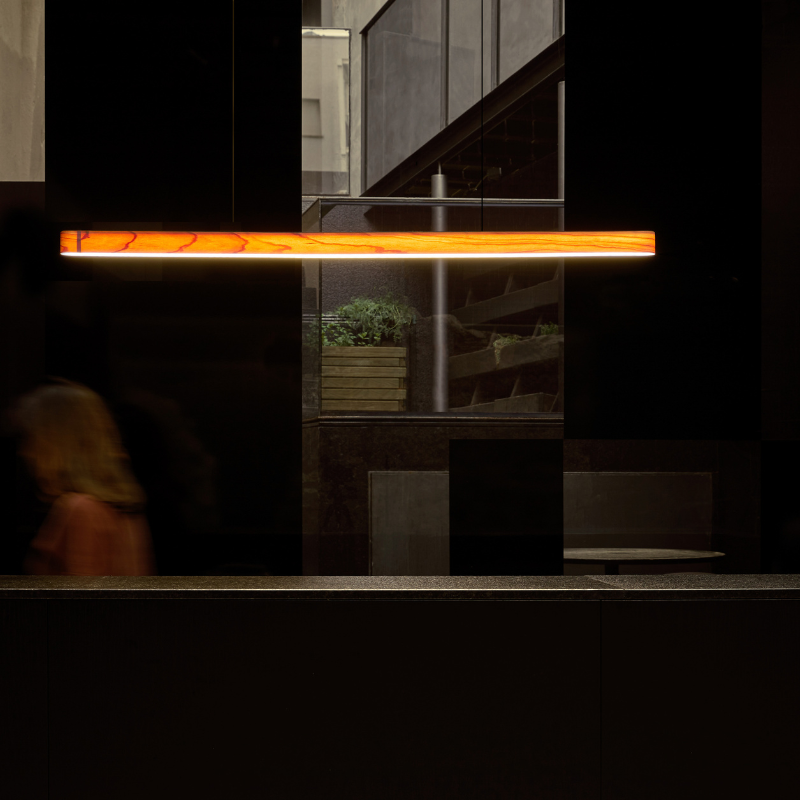 The Short I-Line Suspension from LZF lamps with natural cherry veneer in a living room.