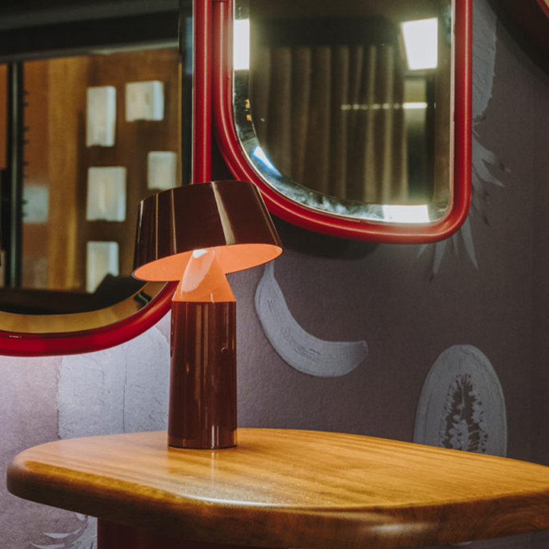 The Bicoca Portable Table Lamp from Marset in red wine in an office.