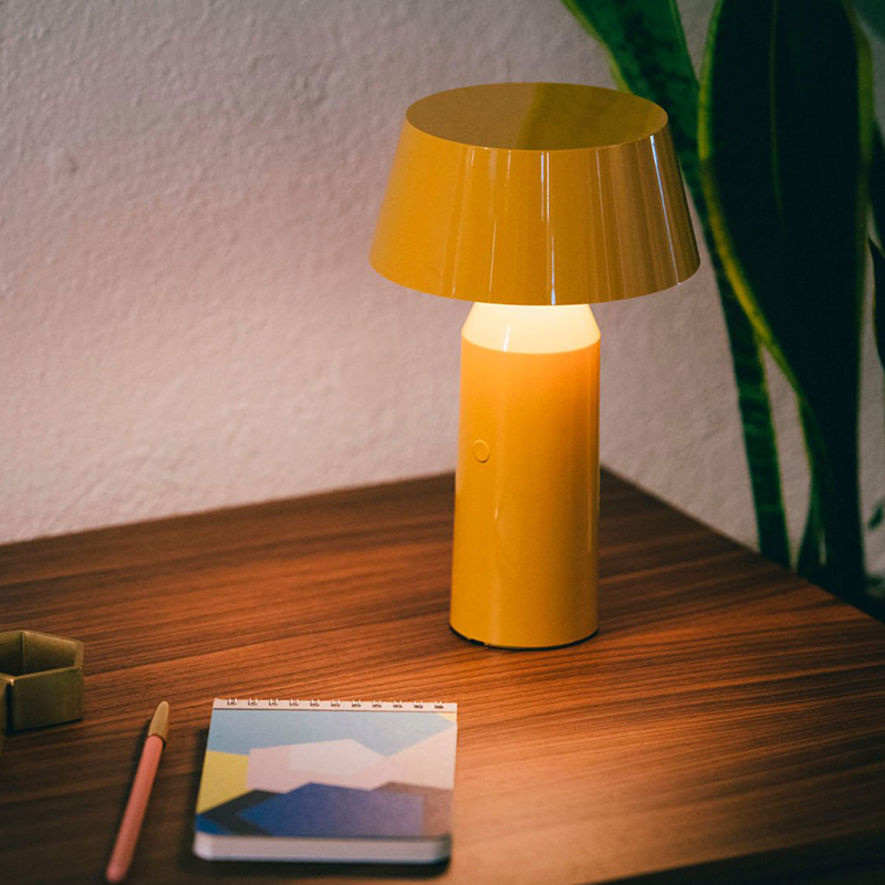 The Bicoca Portable Table Lamp from Marset in yellow in a study area.