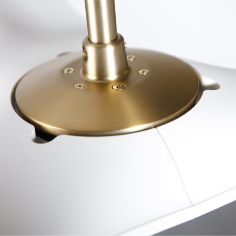 The satin brass and matte white IC/Brisa DC - 56″ from Modern Fan Co. shown close up within a living room.