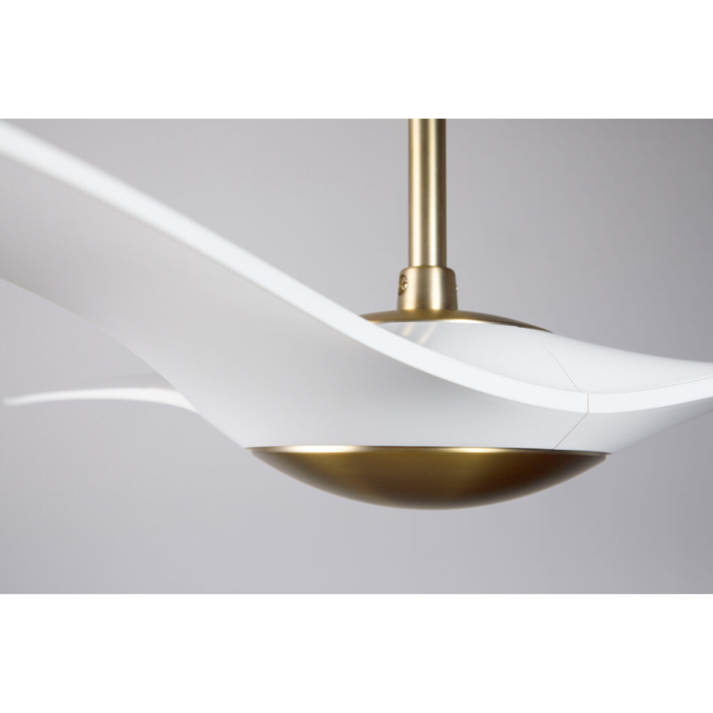 The satin brass and matte white IC/Brisa DC - 56″ from Modern Fan Co. in a view from the side within a living space.