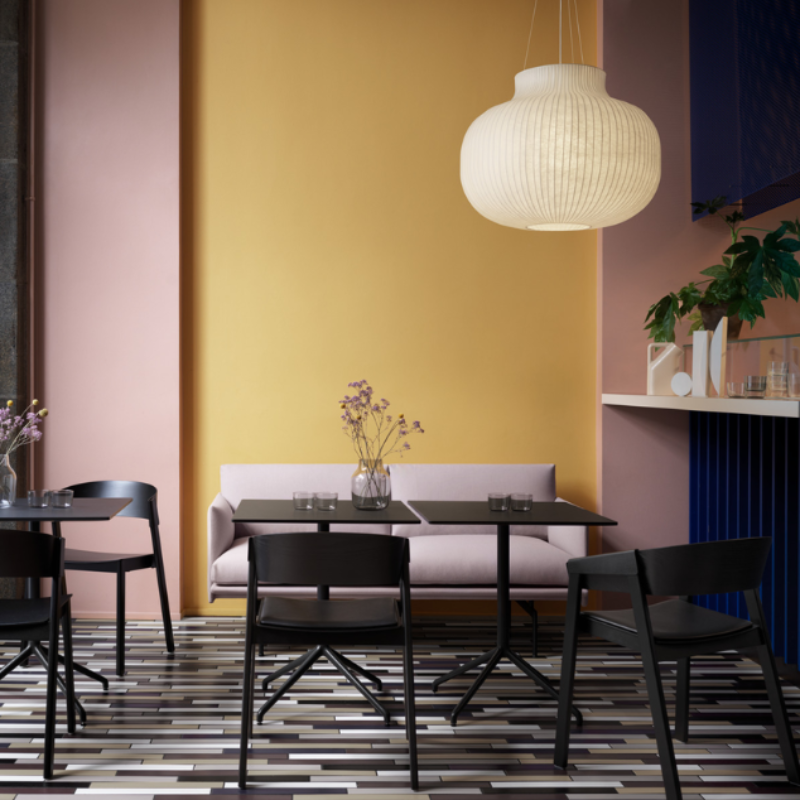 The Cover Armchair from Muuto in black within a restaurant.