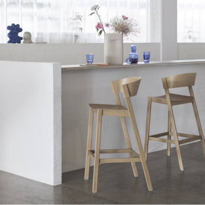 The Cover Counter Stool from Muuto in oak under a kitchen island.