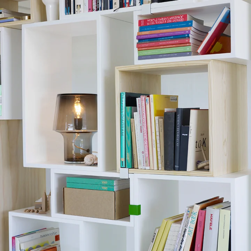 White bookshelf with books and a glass lamp in a living room setting