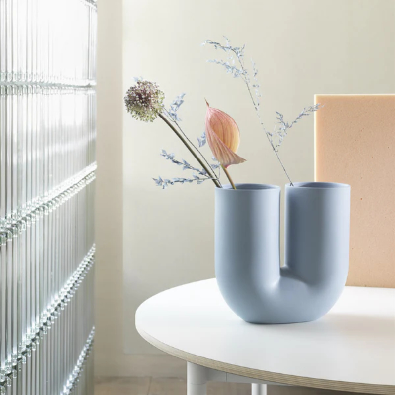 The Kink Vase by Muuto in light blue within a living room.