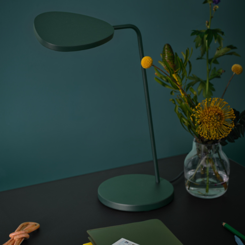 The dark green Leaf Table Lamp from Muuto on a desktop.