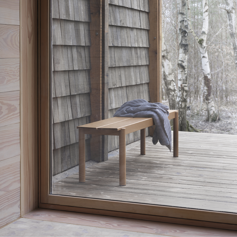 The burnt orange Linear Steel Bench from Muuto in an outdoor living space.