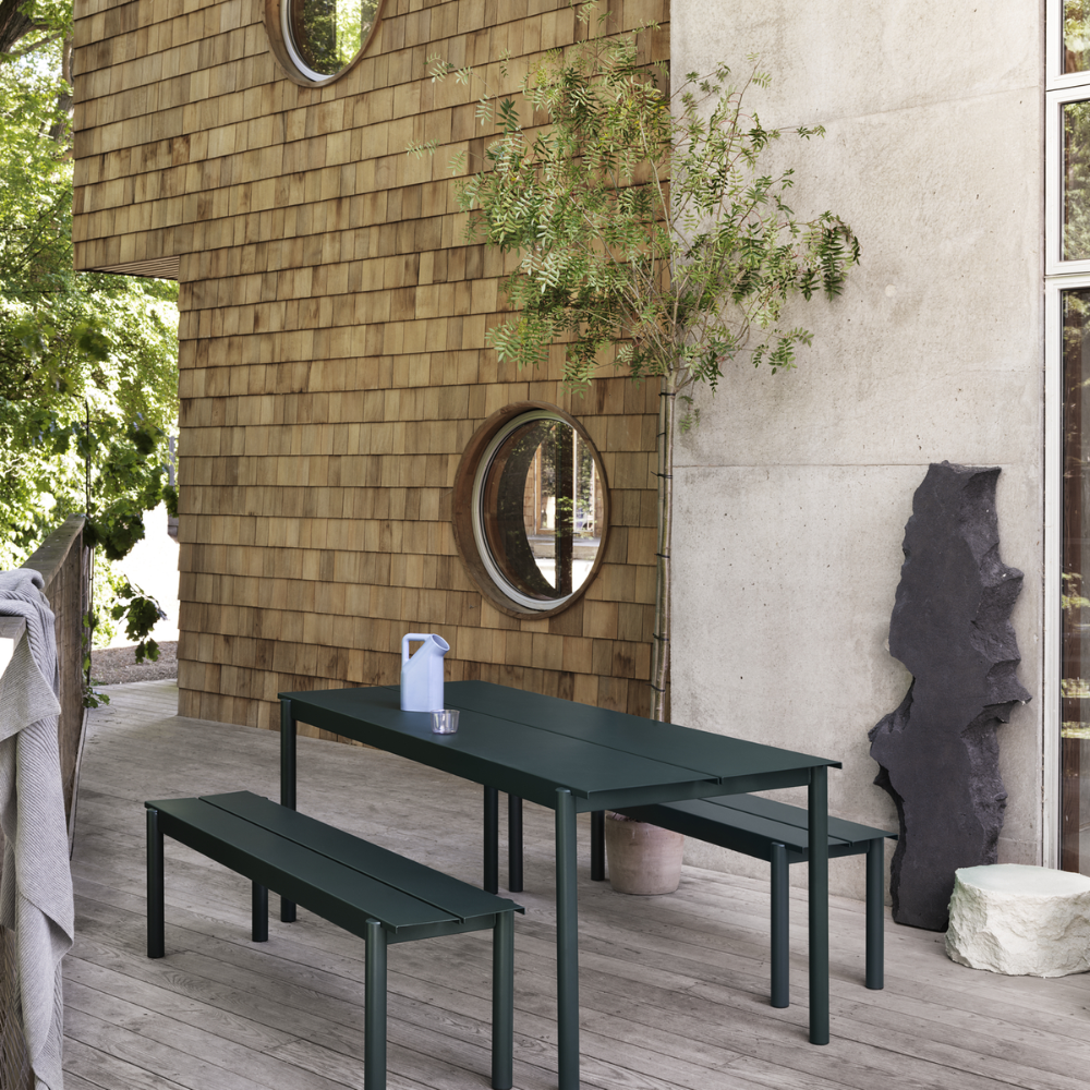 The dark green Linear Steel Bench from Muuto used as patio furniture.