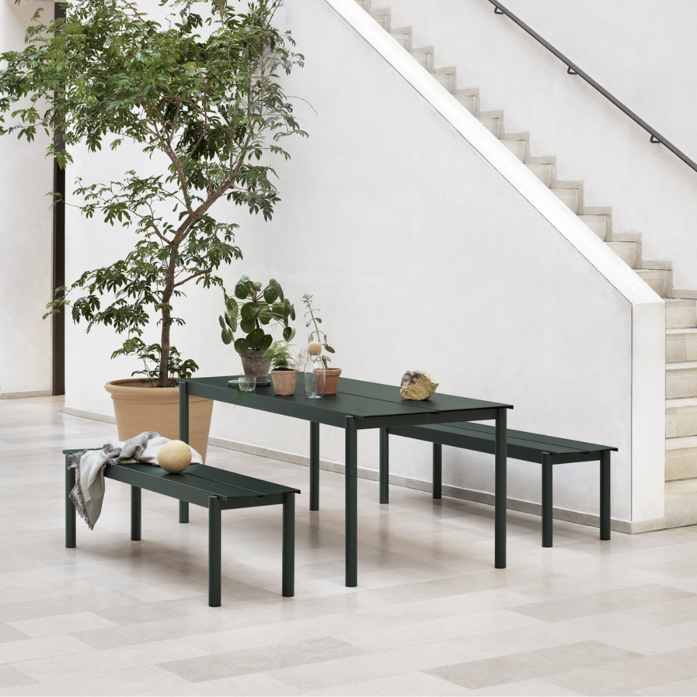 The dark green Linear Steel Table from Muuto in an indoor dining area.