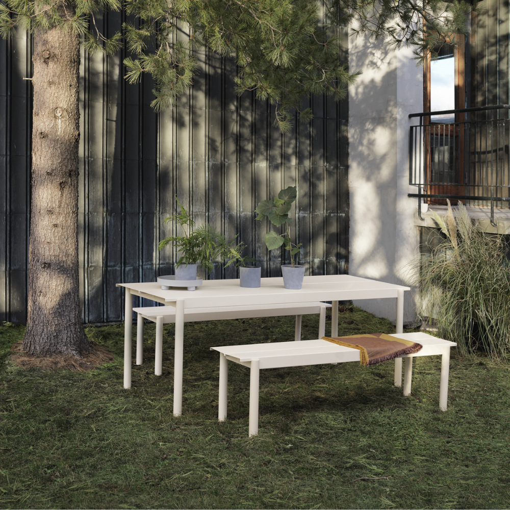 The gray Linear Steel Table from Muuto in a garden.