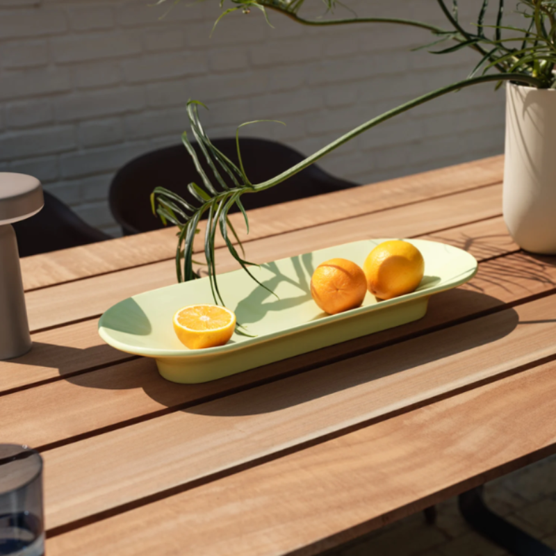 The long Mere Bowl from Muuto in light green within an outdoor dining space.