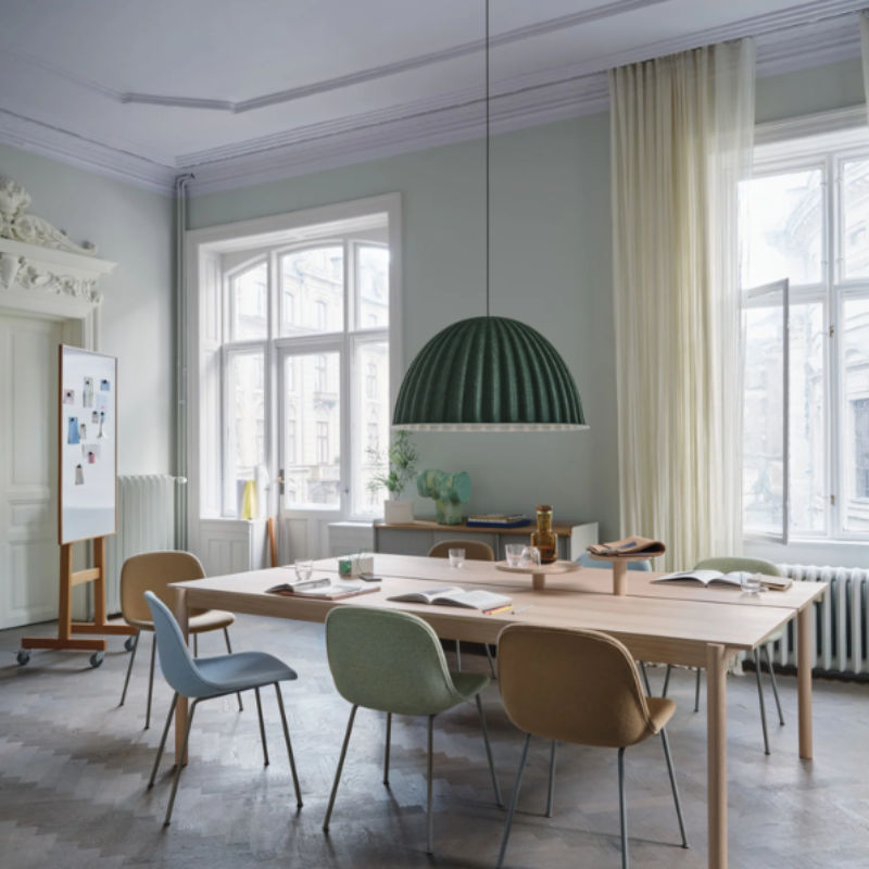 The dark green Under the Bell Pendant Lamp from Muuto in a dining room.