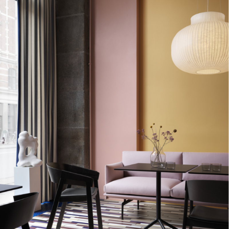 The Upholstered Cover Armchair from Muuto in black with black refine leather in a restaurant.