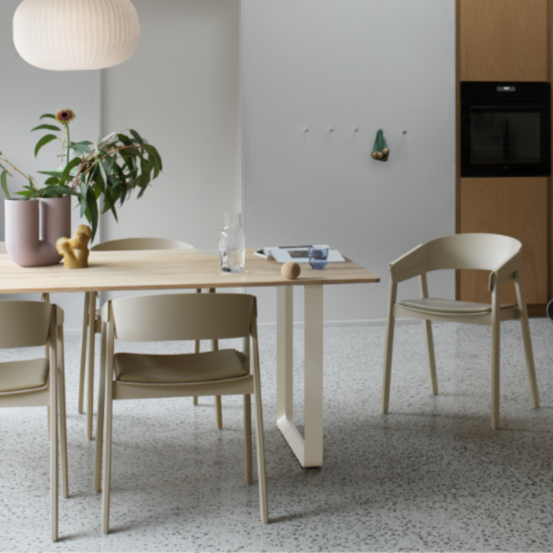 The Upholstered Cover Armchair from Muuto in dark beige with stone refine leather in a dining room.
