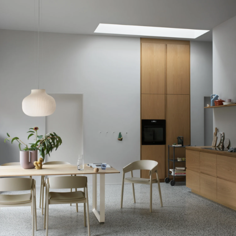 The Upholstered Cover Armchair from Muuto in dark beige with stone refine leather in a kitchen and dining space.