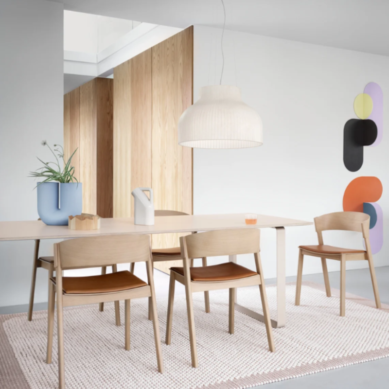 The Upholstered Cover Side Chair by Muuto with cognac refine leather in oak in a dining room.