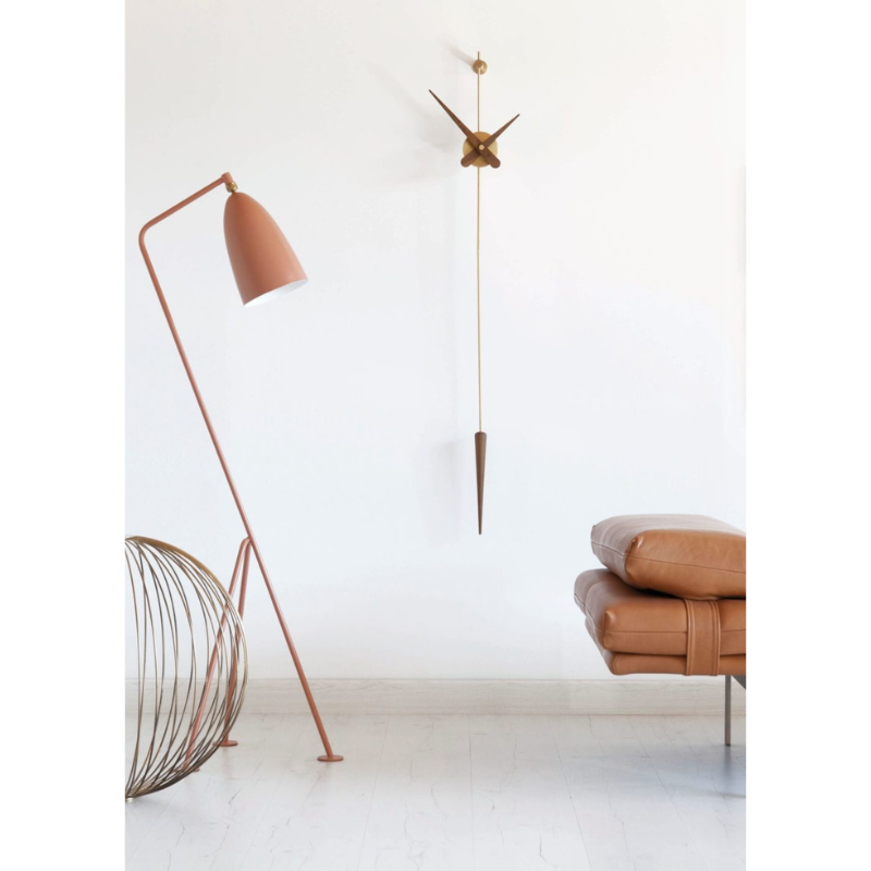 The polished brass and walnut Punto y Coma Clock from Nomon in a home.